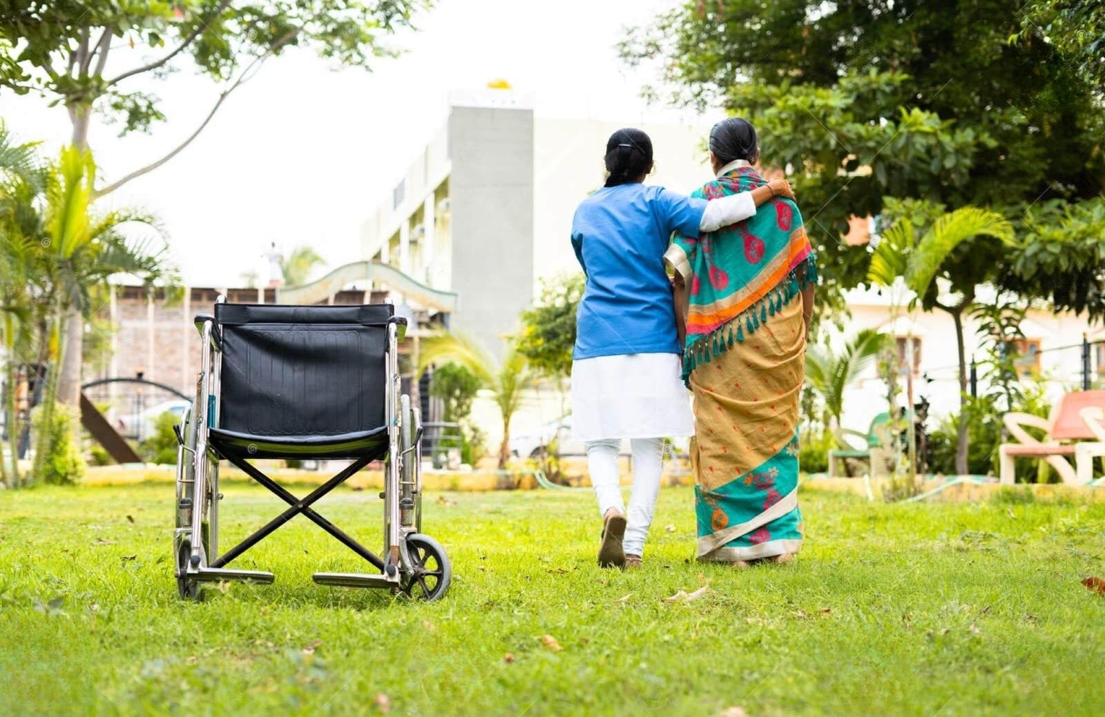 A family caregiver adjusting pillows for an elderly bedridden patient in a home bedroom, bright natural light